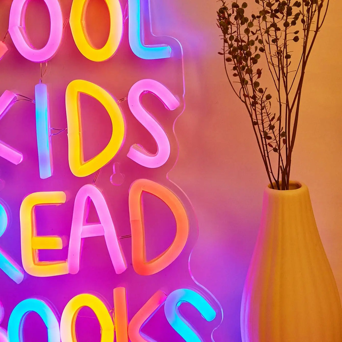 A neon sign spelling out KIDS READ BOOKS with colorful LED lights against a light background.