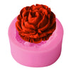 A pink silicone cake decorating mold with a detailed, textured red rose flower molded into the top.