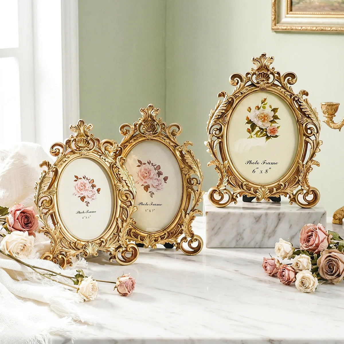 Vintage gold oval resin picture frame displayed on a marble surface with roses and greenery.