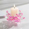 A clear crystal lotus candle holder with a pink wax tealight candle is displayed on a white surface.