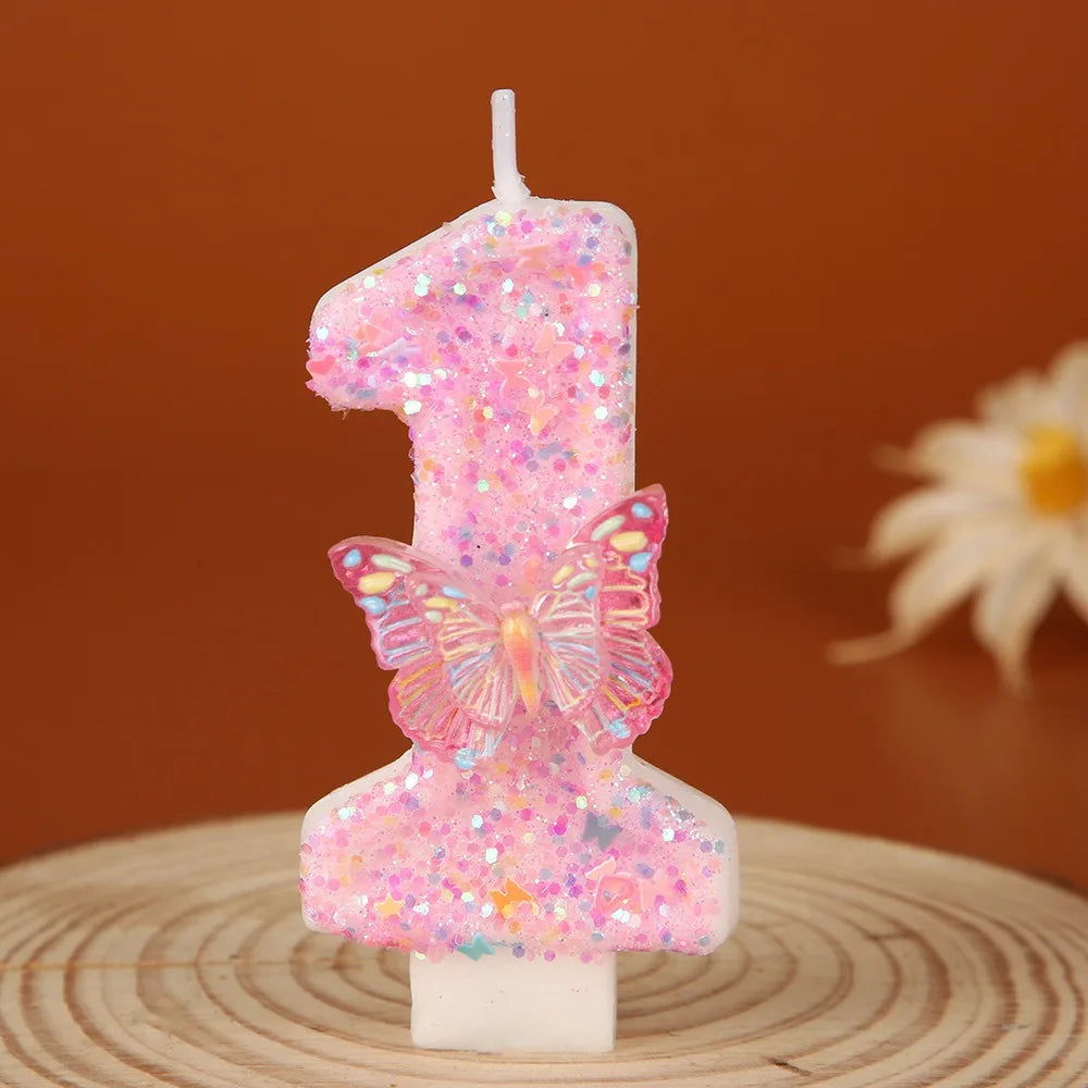 A pink glitter birthday candle shaped like the number one with a butterfly detail.