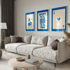 A modern living room features a light sofa, wooden coffee table, and framed art prints on the wall.