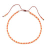 Handmade boho glass bead bracelet with adjustable cord featuring small orange and gold beads.
