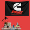 A black flag featuring the white Cummins logo and red Power text mounted on a red wall.
