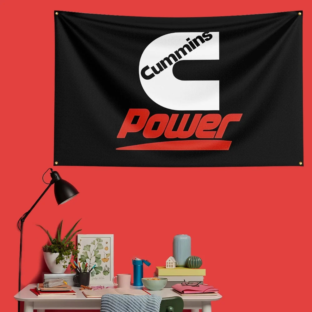 A black flag featuring the white Cummins logo and red Power text mounted on a red wall.
