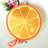 Round orange fruit design foldable hand fan with green foliage in the background