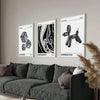 A set of three abstract puppy art canvas prints titled Euphoria, Abundance, and Inspiration displayed on a wall above a dark 