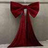 A large, deep red velvet bow with long satin tulle drapes, used for event decoration.