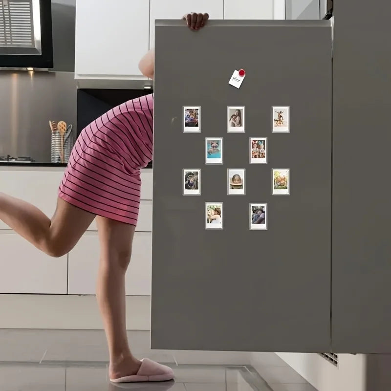 A person is hanging a grid of magnetic acrylic picture frames onto a refrigerator door.