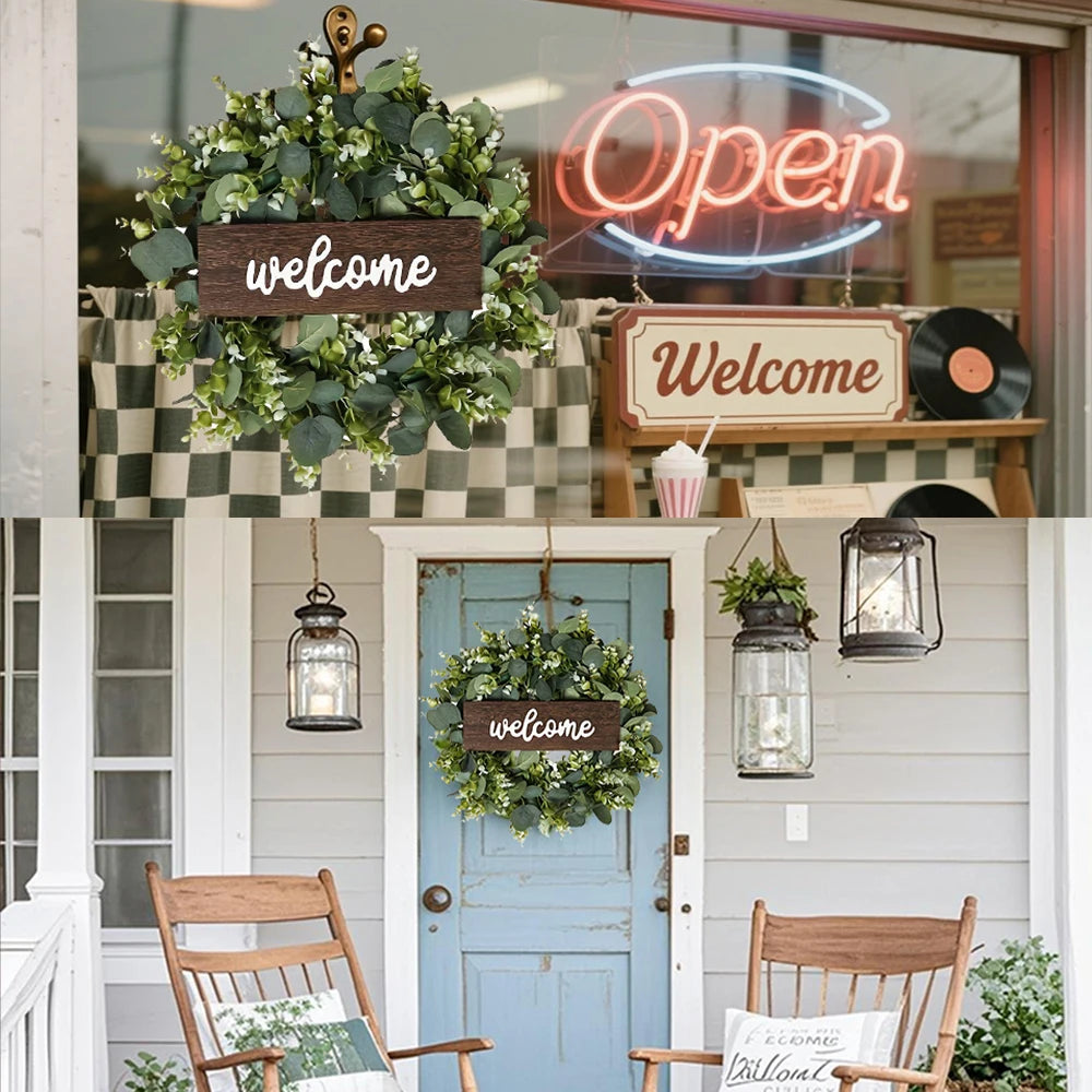 A welcome sign wreath made of artificial eucalyptus hangs on a light blue door.