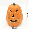 An orange carved pumpkin decoration with a menacing face and glowing features.