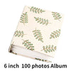A beige photo album with a light green leafy pattern, featuring 100 photos.