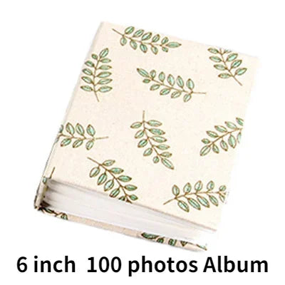 A beige photo album with a light green leafy pattern, featuring 100 photos.