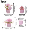 Three pink faux bonsai plants in small pots displayed side by side.