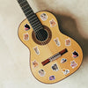 A light wood acoustic guitar decorated with numerous cartoon cat reward stickers.