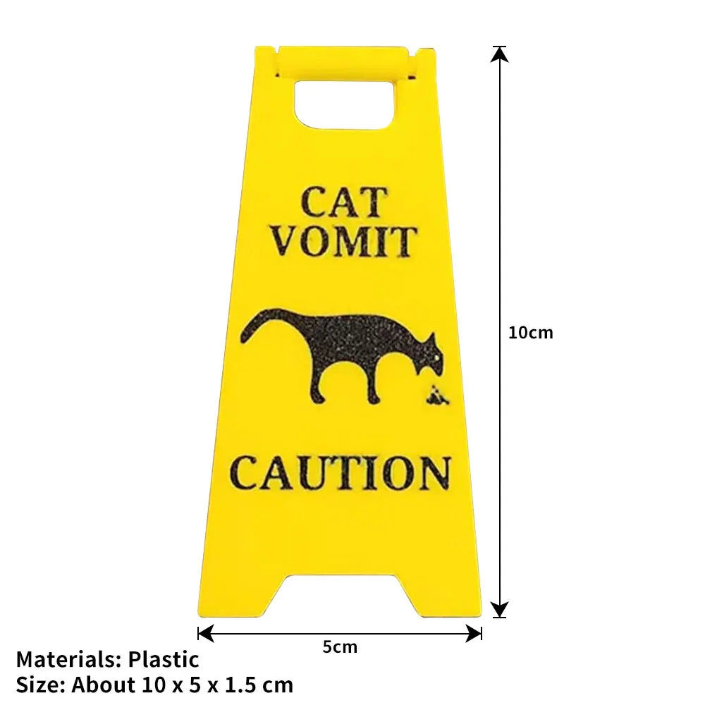 Yellow plastic yard sign with black silhouette of a cat and text warning about cat vomit.