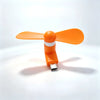 An orange portable USB-C mini fan with soft blades casting a shadow on a white surface.