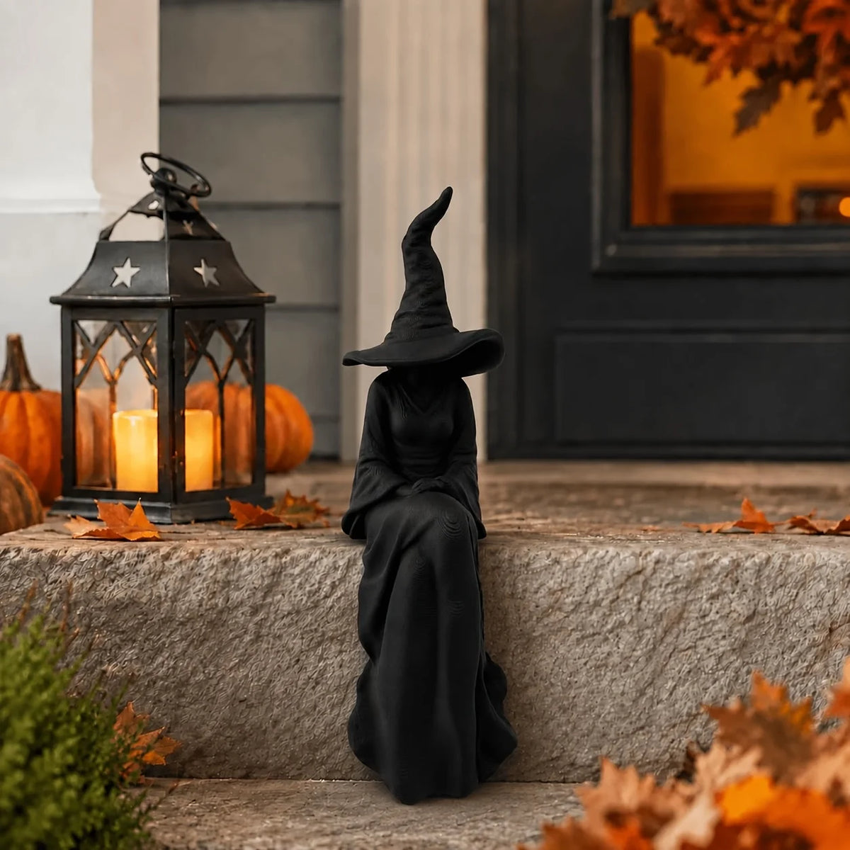 A black witch figurine with a pointed hat and cloak stands on stone steps surrounded by autumn leaves.