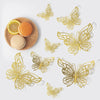 A set of three gold butterfly wall decor pieces displayed on a white background with a citrus fruit.