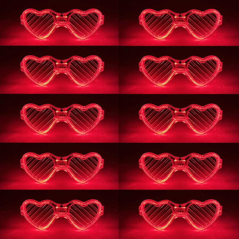 Set fluoreszierender herzförmiger LED-Partybrillen in Rasterform vor dunkelrotem Hintergrund