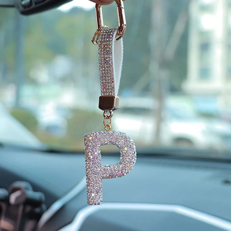 A sparkling pink crystal letter P keychain charm hanging from a gold-colored clasp.