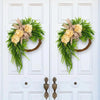 A rustic green hydrangea wreath with a burlap bow hangs on a white door.