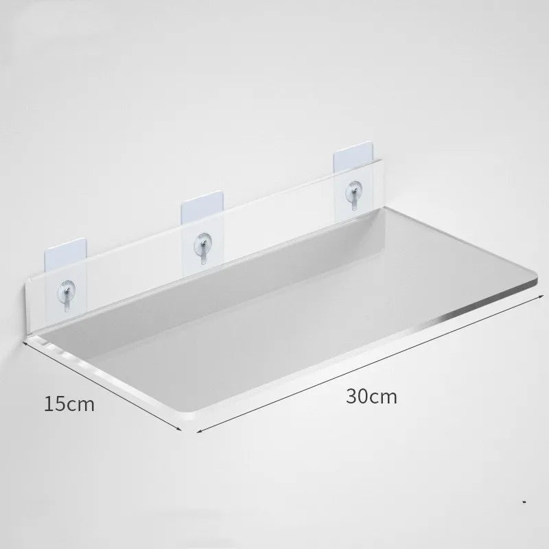 Clear acrylic floating shelf with wall mounts shown mounted on a white wall.