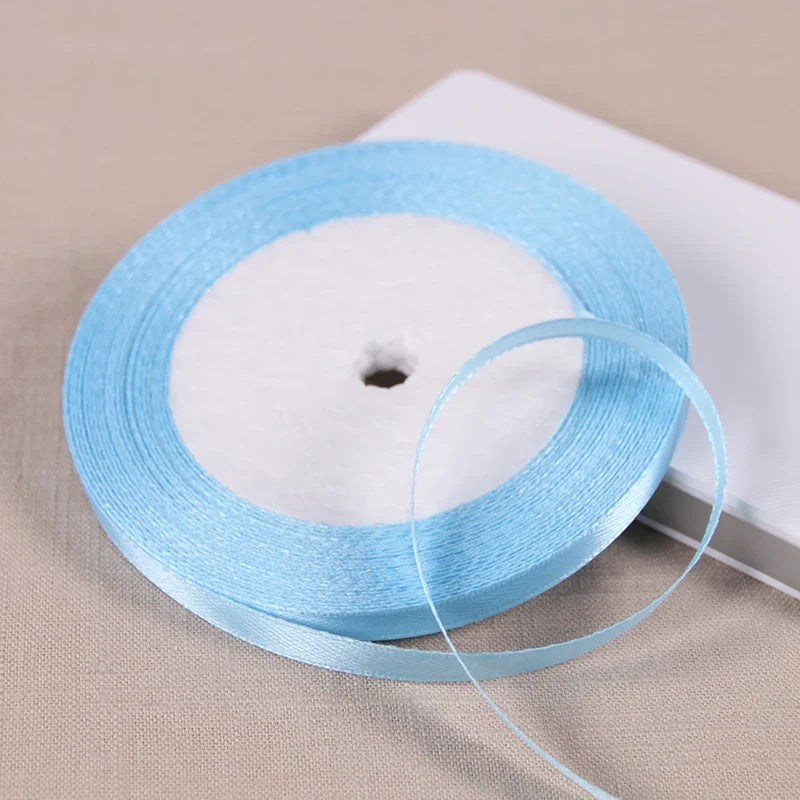 A blue satin ribbon spool with a white core is shown on a light surface.