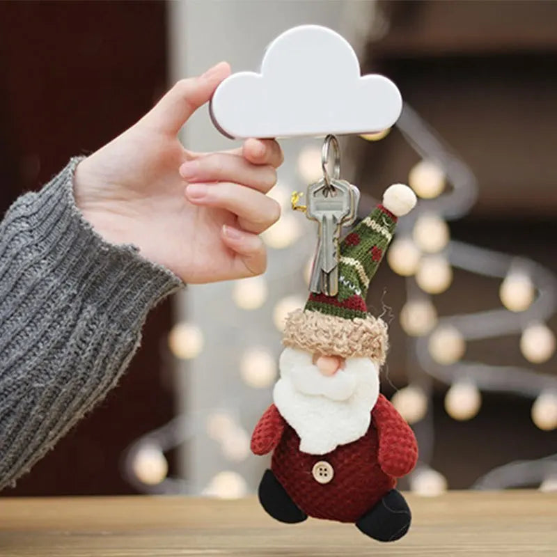 A hand holds a magnetic cloud key hanger with a gnome figure and a white cloud.