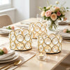 A set of crystal gold votive candle holders and a floral arrangement on a table.