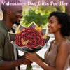 A smiling couple presents a bouquet of red glitter artificial roses to each other.