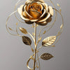 Arte floral de alambre dorado con una rosa y hojas en un tallo esbelto.