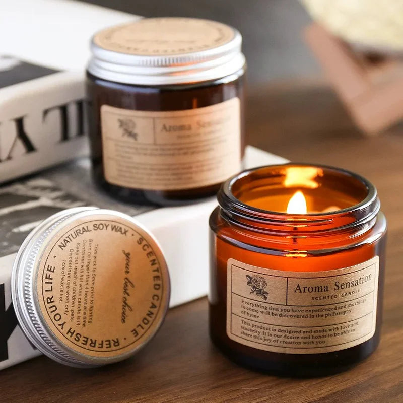 A hand-poured soy aromatherapy candle in a glass jar with an orange flame and a label reading Aroma Sensation