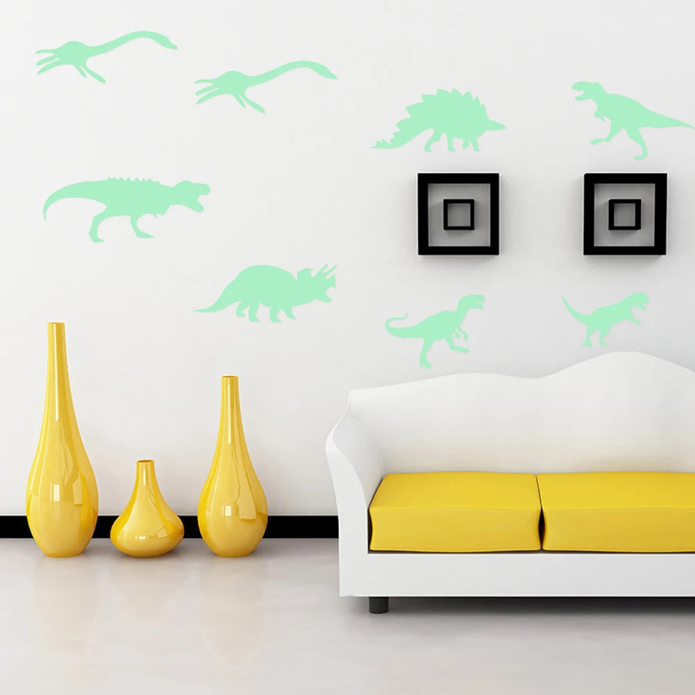 A white wall decorated with light green dinosaur silhouettes and a yellow vase on the floor.