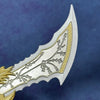 A close-up of a collectible miniature sword featuring intricate etched patterns and a silver blade with gold accents.