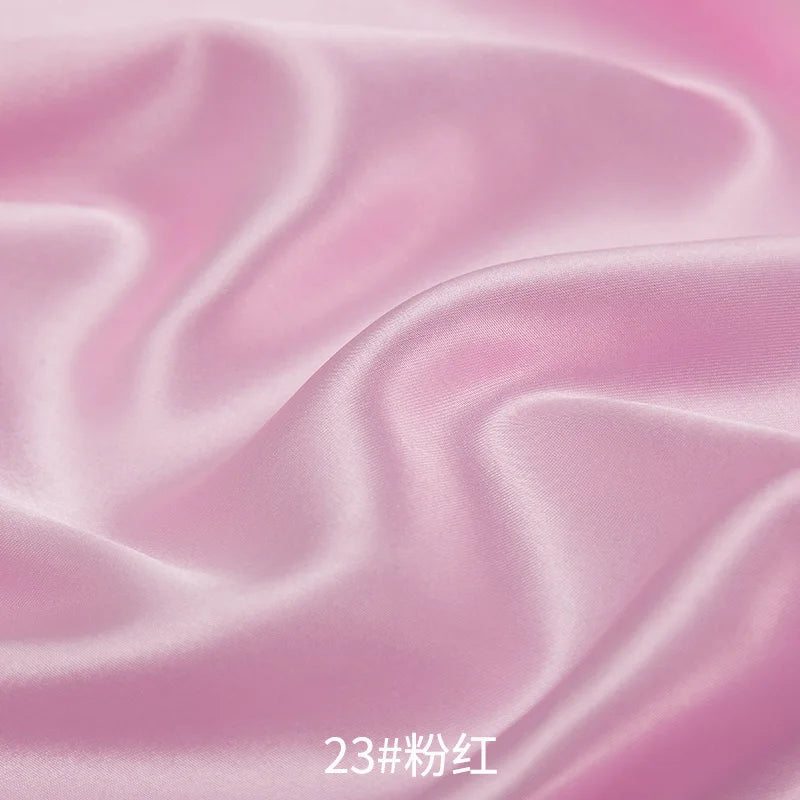 Close-up of flowing pink satin fabric with soft folds and highlights.