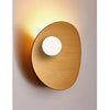 A round, copper-toned wall art piece featuring a circular cutout against a light gray background.