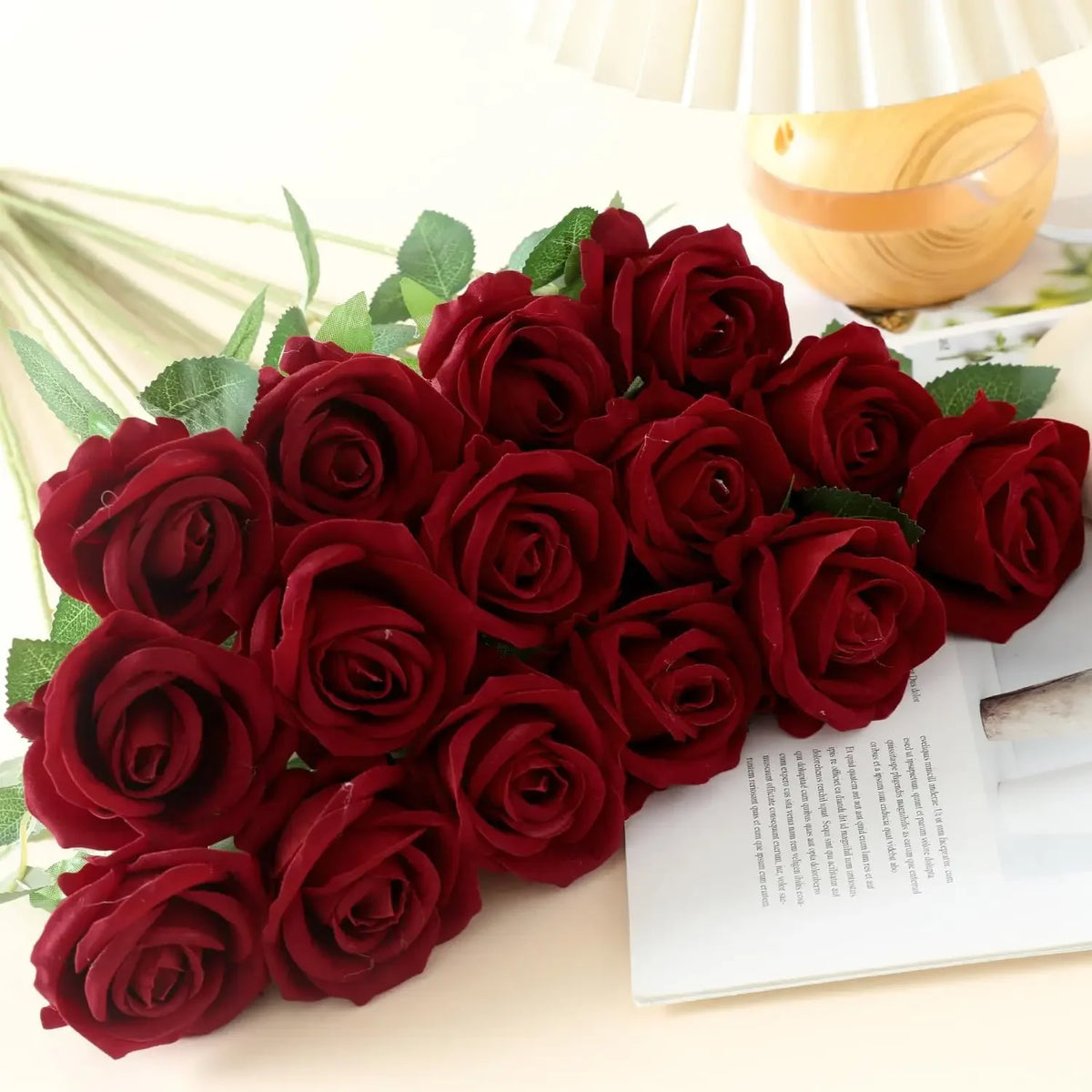A bouquet of deep red velvet artificial roses arranged on a light surface.