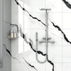 A modern bathroom wall featuring white marble tile with black veining and a chrome shower fixture.