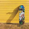 A skateboard featuring a colorful graphic design against a bright yellow wall.
