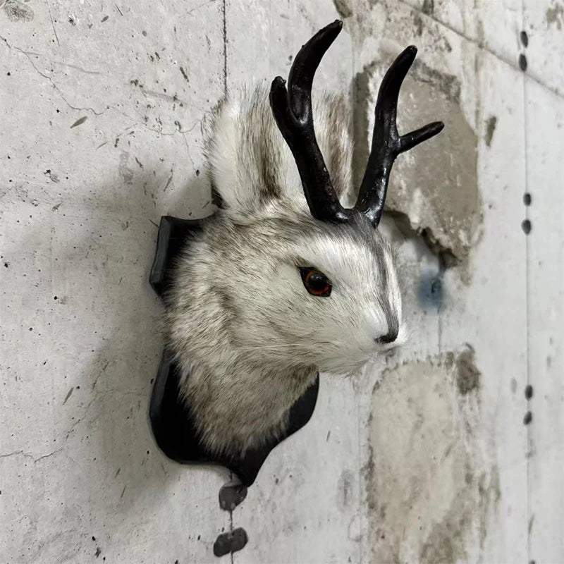 A decorative bunny head with black antlers and white fur mounted on a wall.