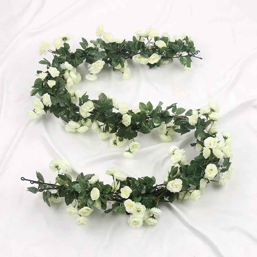A green silk rose vine garland with white flowers used for wedding and home decor.