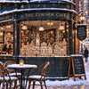 A storefront window decorated with a detailed gingerbread city scene under snow.