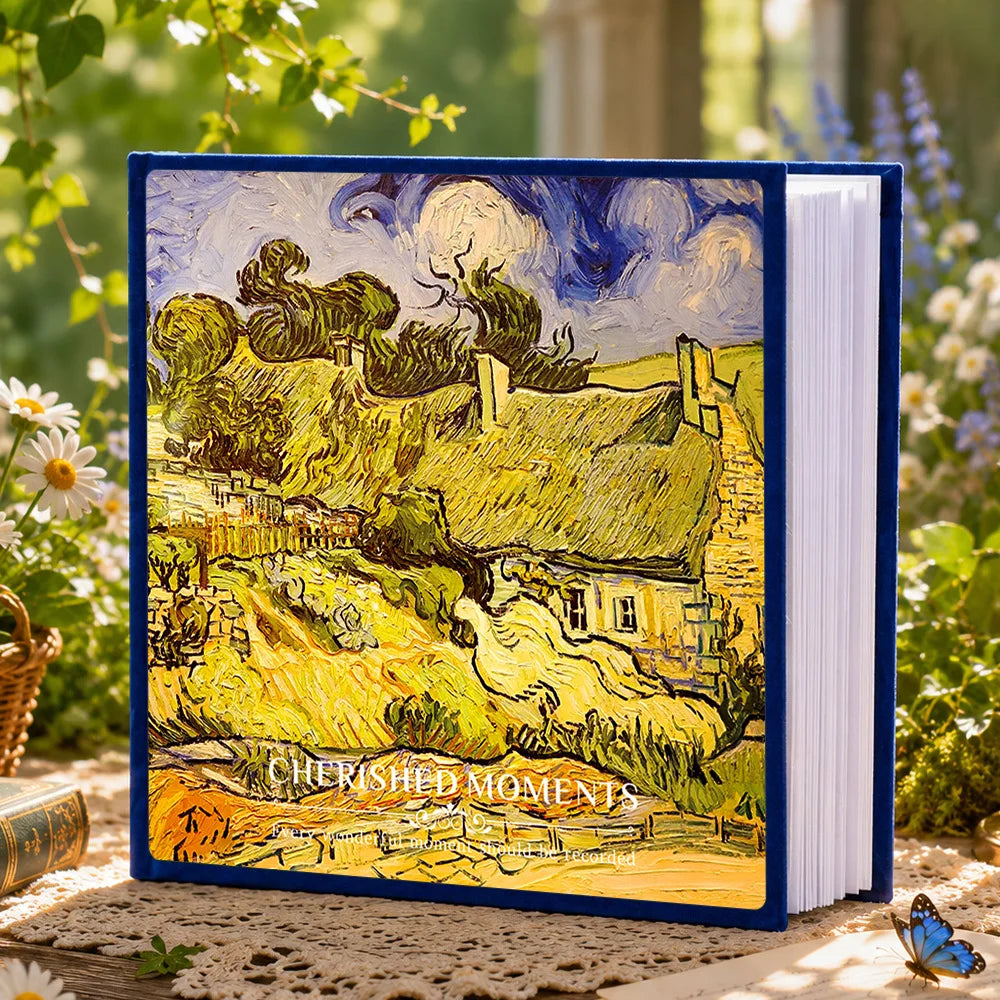 A blue laminated photo album featuring a landscape painting of rolling hills and a sky.
