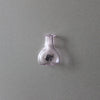 A clear glass bottle or vial with a narrow neck is mounted on a gray wall.