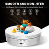 A white electric rotating turntable display stand featuring various stuffed toys on top.