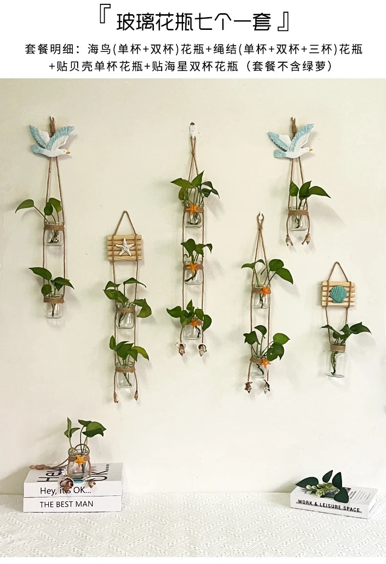 A collection of decorative glass terrariums featuring various indoor plants and floral arrangements hanging on a white wall.