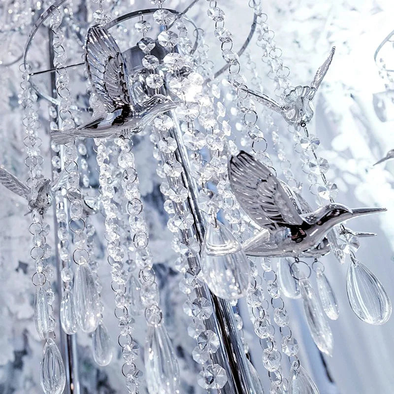 Clear crystal glass strands with silver accents and bird-shaped charms hanging in a vertical display.