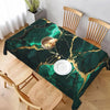 Mantel rectangular de mármol verde oscuro sobre una mesa de madera con sillas, en una habitación luminosa.
