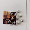 A set of silver star-shaped fridge magnets displayed on a card against a white background.